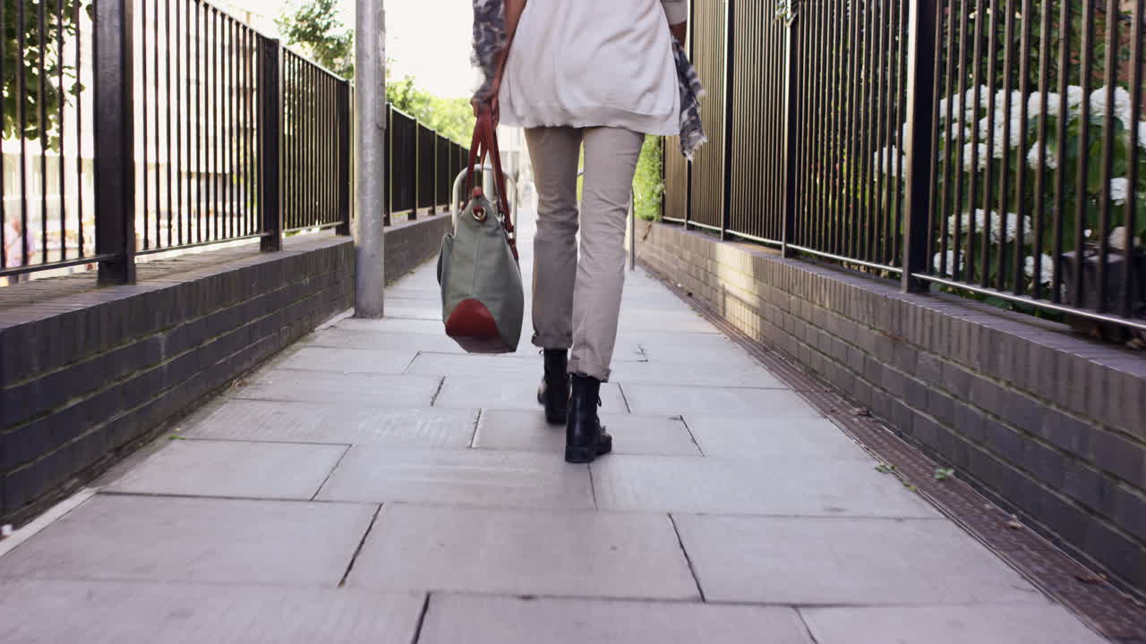 Detail of woman's feet walking through city on pavement from behind