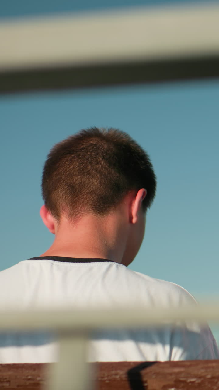 머리에 안경을 쓴 여자가 뒷면을 바라보며, 에 앉아 있는 남자를 향해 따뜻하게 미소 짓고, 철의 레일링과 밝은 하늘에 여 있다.