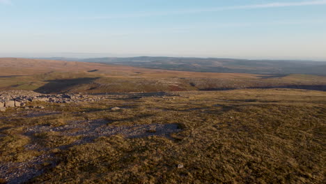 Un-Dron-Aéreo-De-4k-Panorámico-Y-Moviéndose-En-Un-Paisaje-Rocoso-Con-Un-Parque-Eólico-Y-Campos-En-Segundo-Plano-En-Brecon-Beacons,-Gales,-Reino-Unido