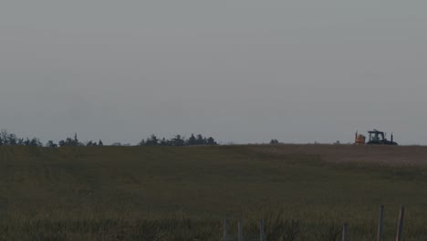 Tractor-driving-through-a-field-on-a-dark-overcast-day