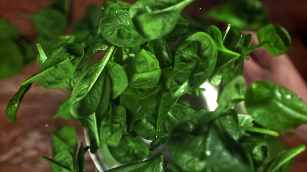 Foglie di spinaci verdi fresche che volteggiano al rallentatore