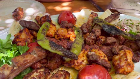 eating a traditional turkish big meat platter mixed grill with vegetables and fresh pide ekmek bread in bodrum turkey, authentic tasty food, 4k shot