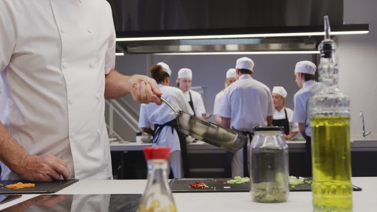chef masculino caucásico profesional en una cocina de un restaurante preparando comida usando una sartén