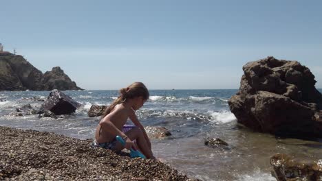 long-haired girl playing with pebbles at the beach in spain