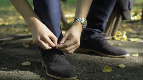 los cordones de los zapatos masculinos se atan el parque al aire libre a lo largo de listo para usar