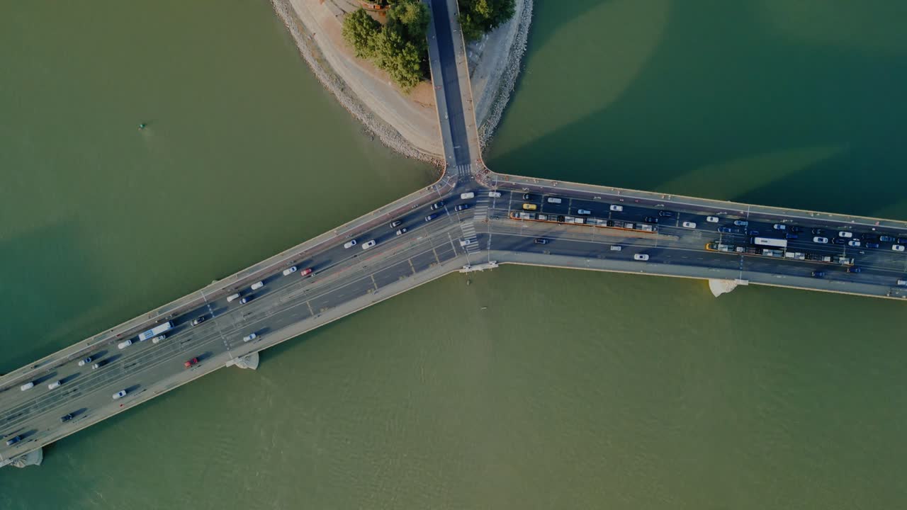 Top down drone orbit bridge and green river water in Budapest with vehicle movement, top shot