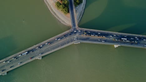 top down drone orbit bridge and green river water in budapest with vehicle movement, top shot