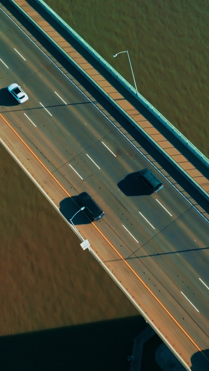 Cars on the bridge with one-direction road. Automobile bridge with pedestrian zone on the right. Top view. Vertical video