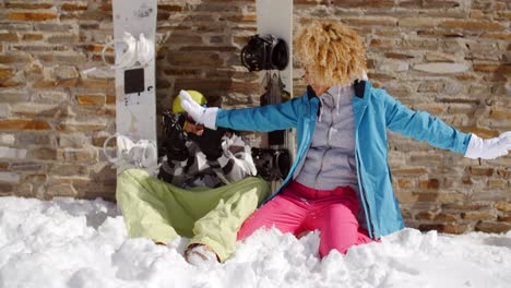 laughing woman sitting next to friend in snow