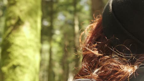 woman hiker with black hat in the forest gazing at evergreen trees in beautiful nature