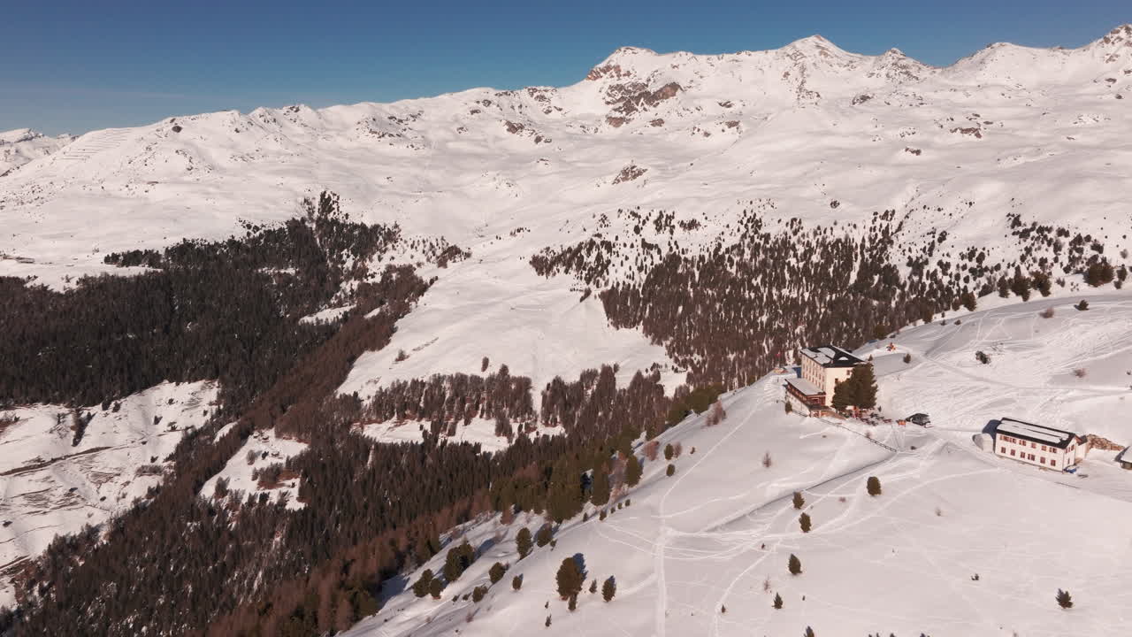 Drone aerial of Hotel Weisshorn, Switzerland. Iconic alpine hotel surrounded by snowy peaks and forests, offering breathtaking mountain scenery for travel, tourism and cinematic stock footage