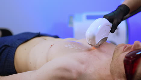 hair removal procedure with the help of elos epilation. cosmetologist moves the equipment by the make chest.
