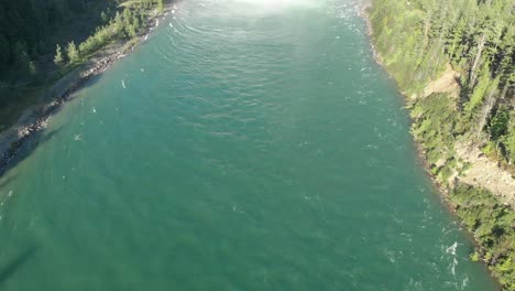 Toma-Aérea-Inclinada-Hacia-Arriba-De-La-Represa-De-Revelstoke-Al-Mediodía,-Rodeada-De-Montañas-Y-Pinos