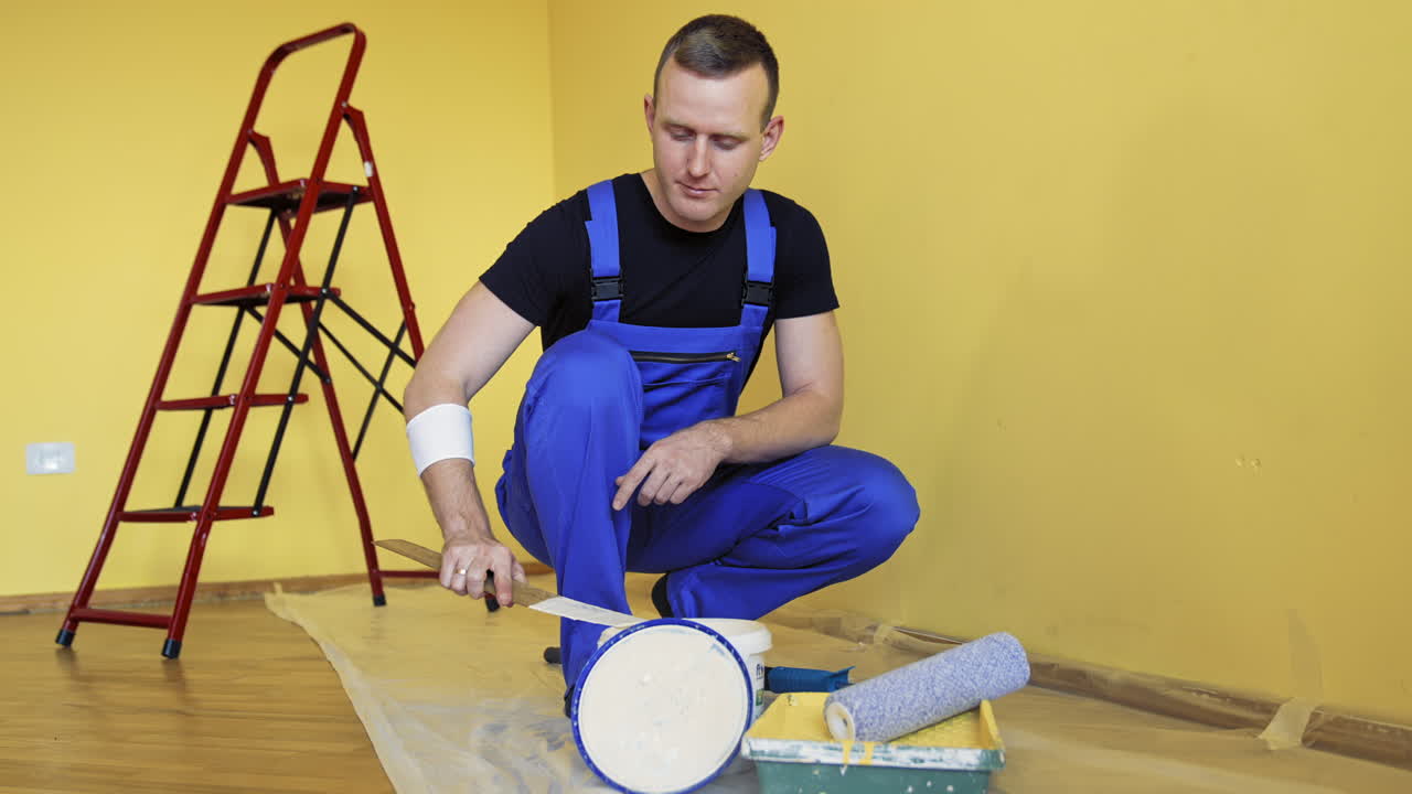 Handsome painting master doing room renovation. Professional painter renovating the room.