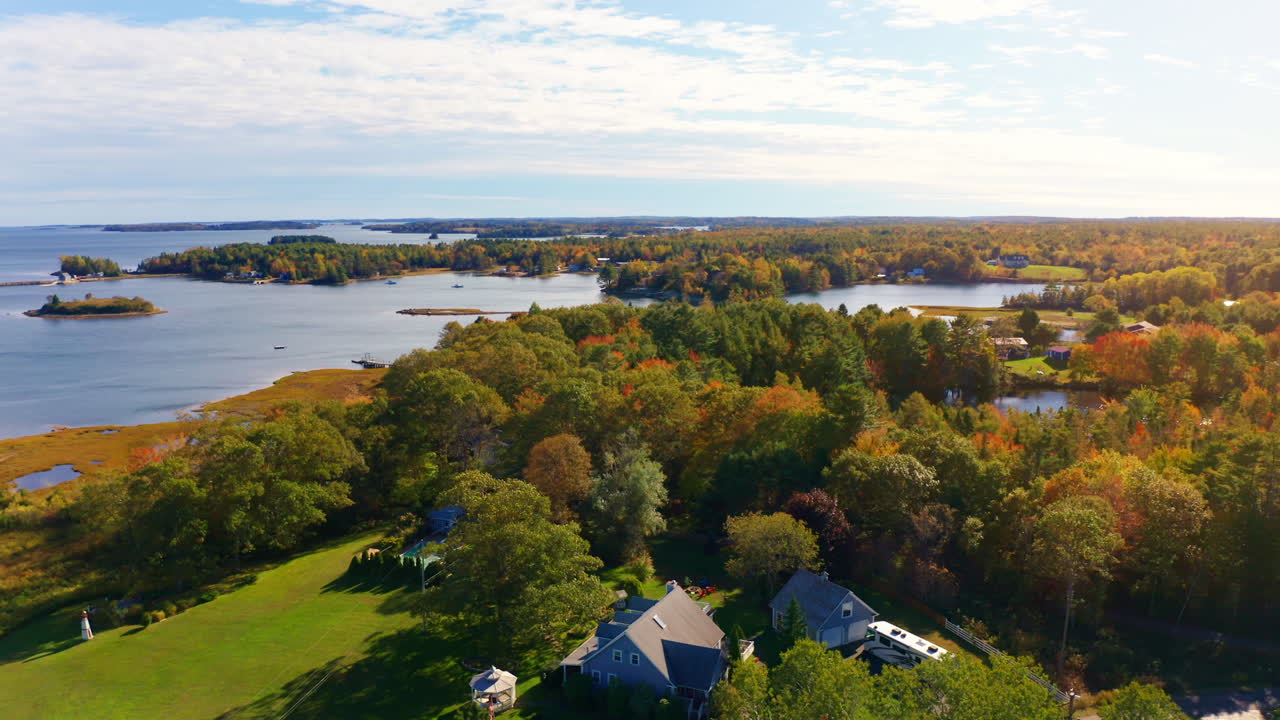 Aerial drone shot over the coastline of Oak Island, Nova Scotia, Canada.
High view of the sea, autumn colorful trees foliage. Picturesque landscape. Fall vibrant colors.
