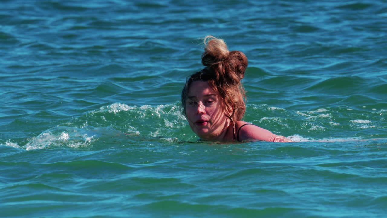 A woman swims alone in the clear blue waters of the Mediterranean Sea near Cannes, France
