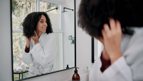 woman styling hair in bathroom mirror