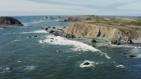 Tracking-drone-footage-of-sea-cliffs-at-the-Pacific-ocean,-on-a-sunny-day