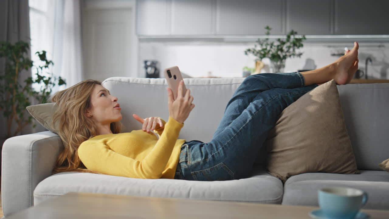 Smiling woman talking videocall laying home sofa. Lady enjoying virtual call