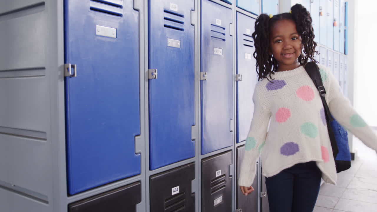 Smiling girl with backpack standing by lockers in school hallway, copy space