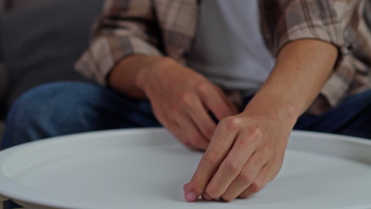 Close-up of young husband slowly removing gold wedding ring and placing on table