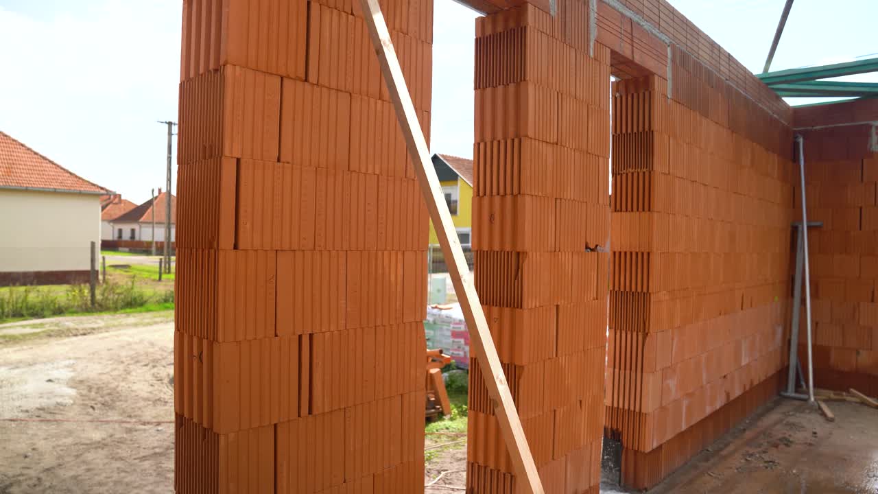 Brick wall with window and door openings under construction on suburban street