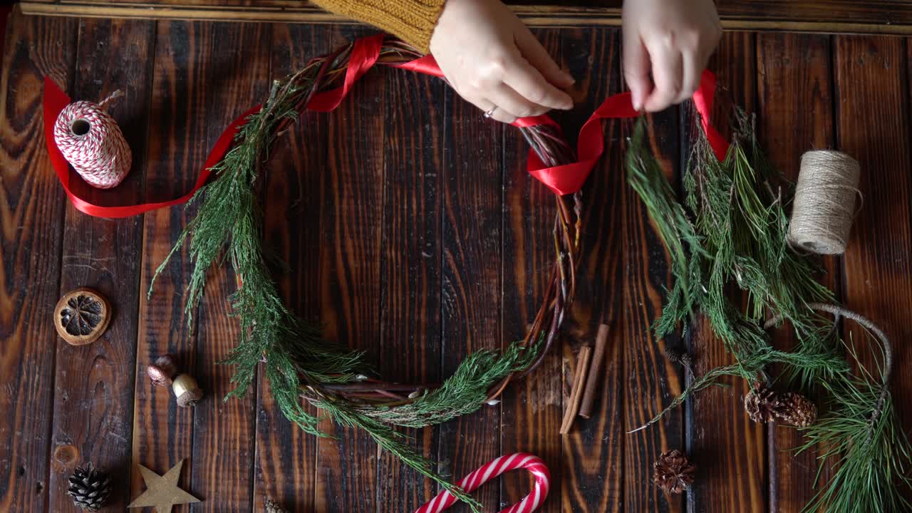 mujer haciendo una corona de navidad en fondo de madera oscura