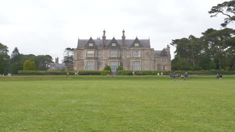 Muckross-House-Museum-With-Tourists-In-The-Garden-In-Killarney,-County-Kerry,-Ireland