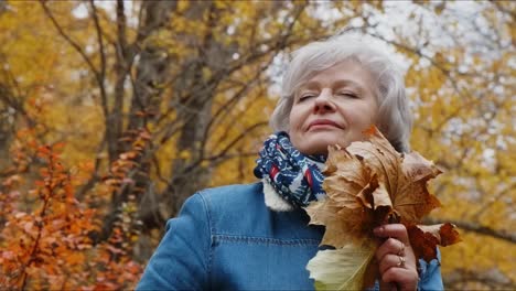 senior woman enjoying autumn leaves