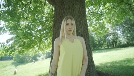 woman in yellow dress dancing by tree in summer park