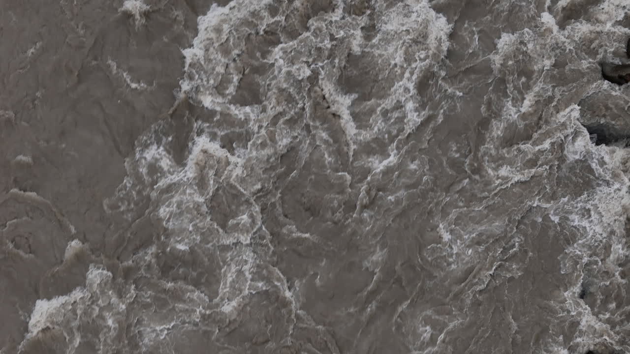 tomada por un avión no tripulado de enormes olas de agua que fluyen rápidamente en un río durante la época del monzón en nepal, la escena captura la situación desastrosa y alarmante causada por las fuertes lluvias, destacando el riesgo de inundaciones