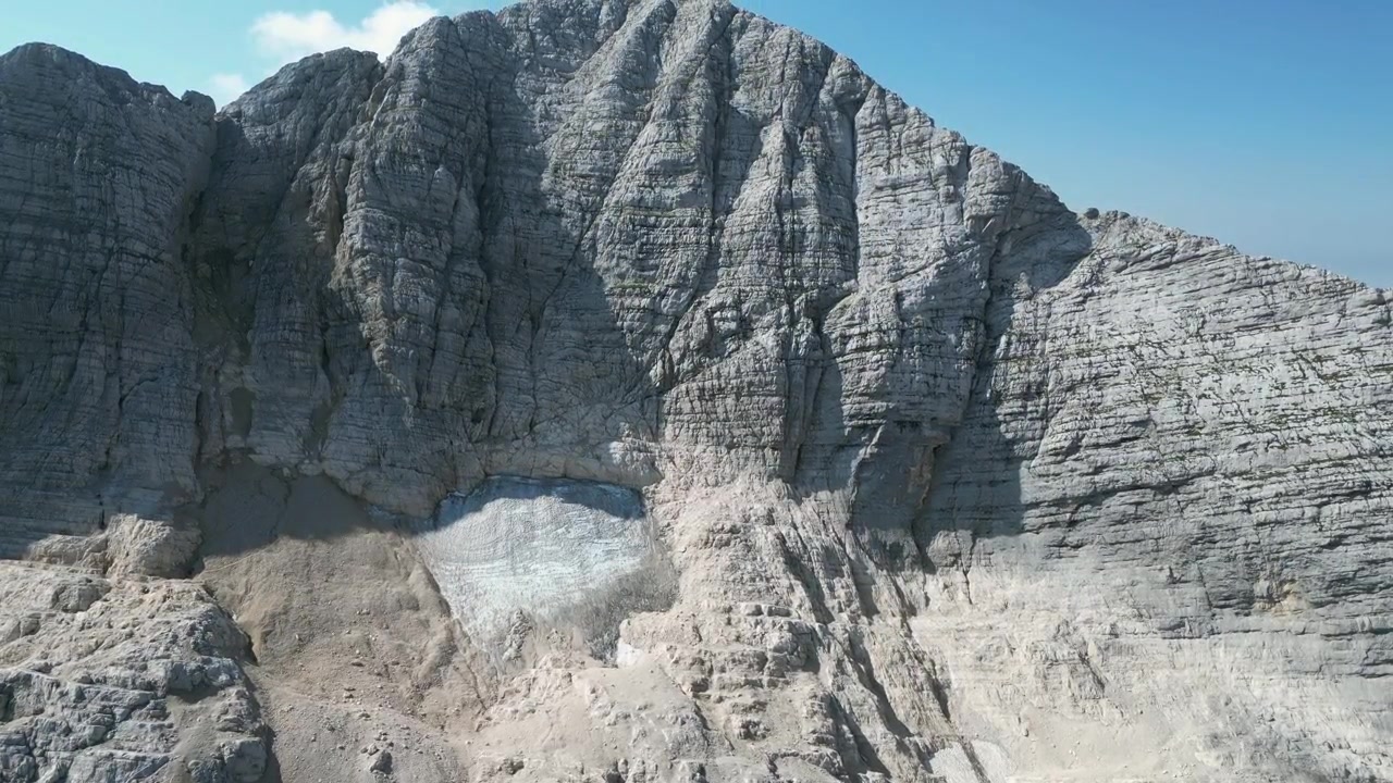 Riprese aeree con drone del Monte Canin in Friuli, Italia: cime calcaree frastagliate, creste rocciose e un drammatico terreno alpino sotto un cielo sereno. Ideale per progetti di natura, viaggi e attività all'aperto