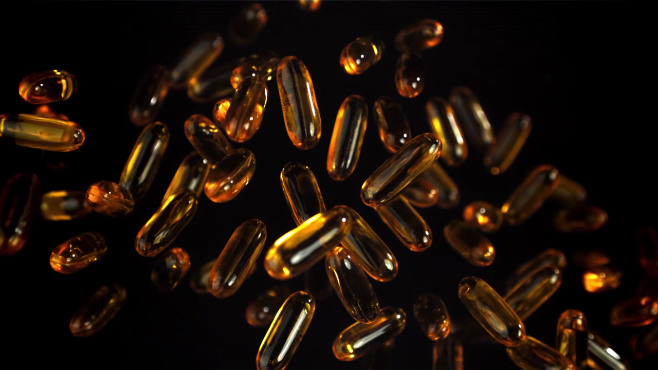 Capsule Omega-3 ambrate che fluttuano su uno sfondo nero