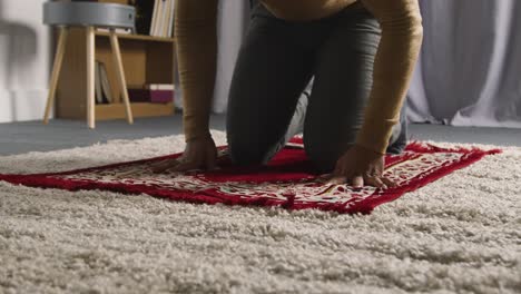 hombre musulmán en casa arrodillado sobre una alfombra de oración y orando
