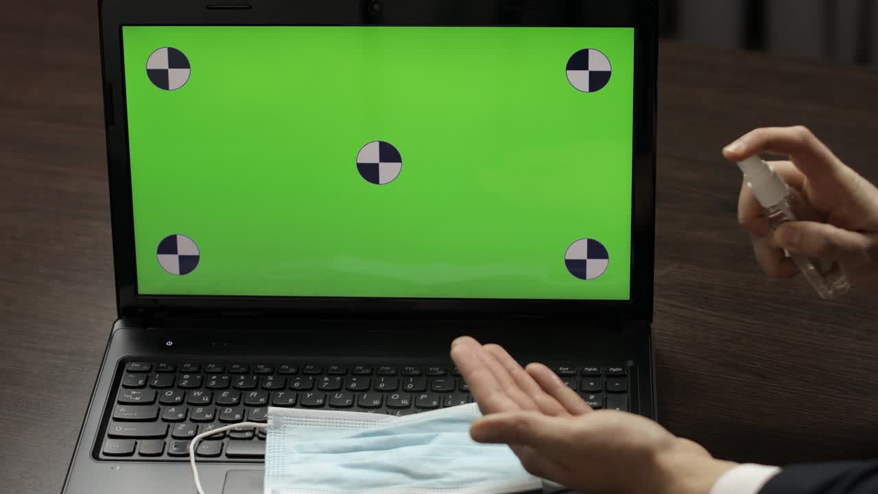 la mano del hombre toma desinfectante y lo usa cerca de la computadora portátil con pantalla verde. coronavirus