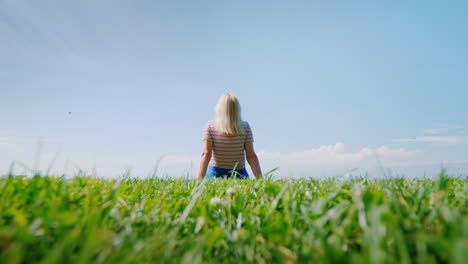 Eine-Frau-Sitzt-Auf-Perfekt-Geschorenem-Gras,-Das-In-Einen-Klaren-Blauen-Himmel-Geht