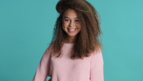mujer caucásica de cabello rizado con los pulgares hacia arriba delante de la cámara.