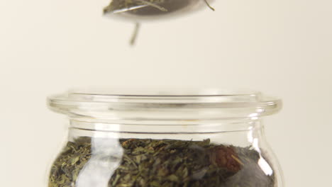 toma lateral de una cuchara sacando un montón de hojas de té verde de un frasco de vidrio en 100 fps