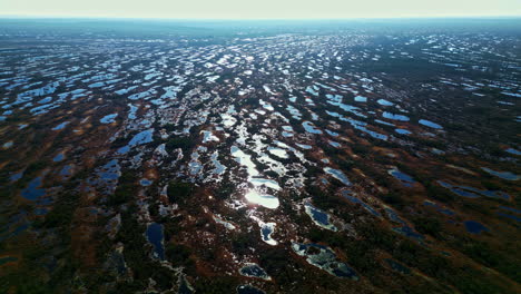 Low-water-puddles-shine-shimmer-from-bright-sunlight,-remnants-from-after-rainstorm-flooding-in-deserted-area