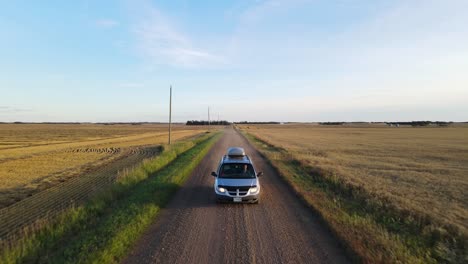 coche plateado que viaja a través de la vasta y seca campiña del centro de alberta