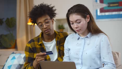 young multiethnic couple doing shopping in internet with credit card at home