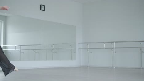 fit girl in black clothes performing contemporary. female dancer shows flowing motions, body and hands waves at white room. modern ballet dance choreography. young woman is moving smoothly