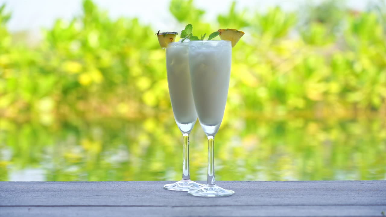 Two white Cold Cocktail Drinks with Pineapple By A Swimming Pool