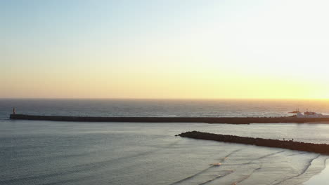 toma aérea izquierda de la puesta de sol sobre el rompeolas de azurara, portugal
