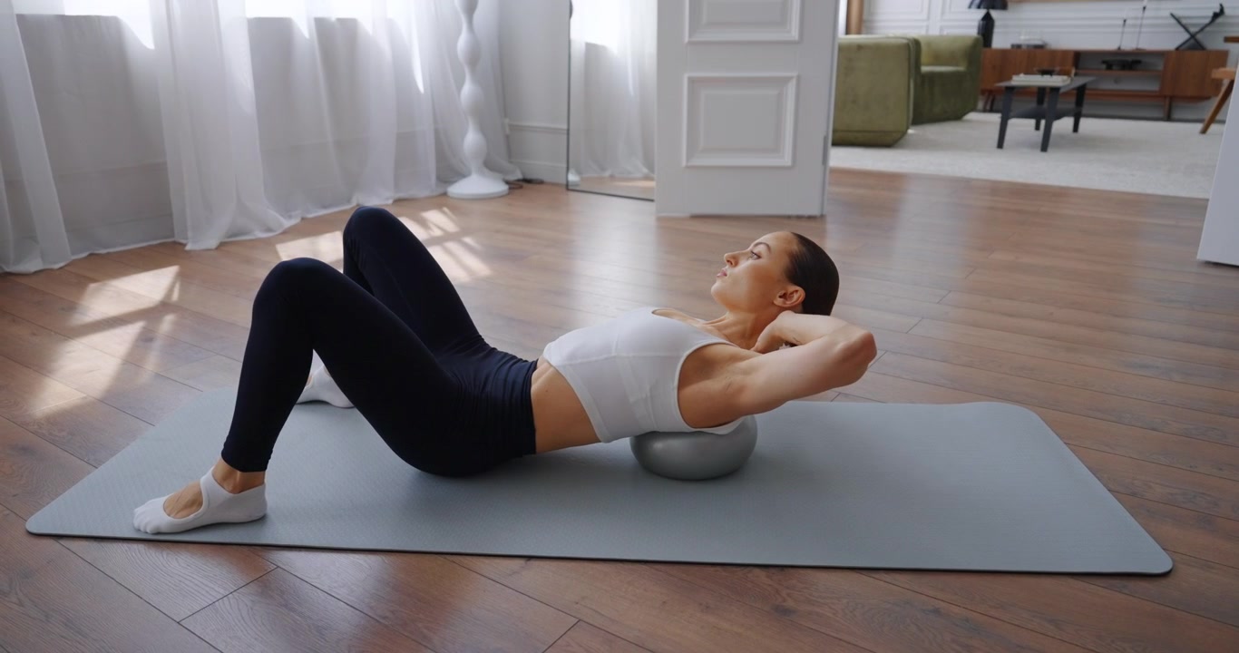 Fitte Frau führt Bauchpressen mit einem Gymnastikball aus.
