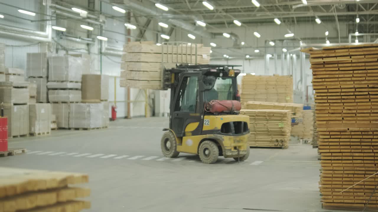 Gabelstapler transportiert Holzbohlen in einem großen Industrielager