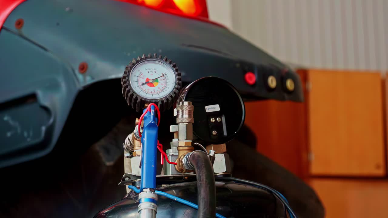 Closeup of a pressure gauge and pipes near machinery indoors, industrial scene
