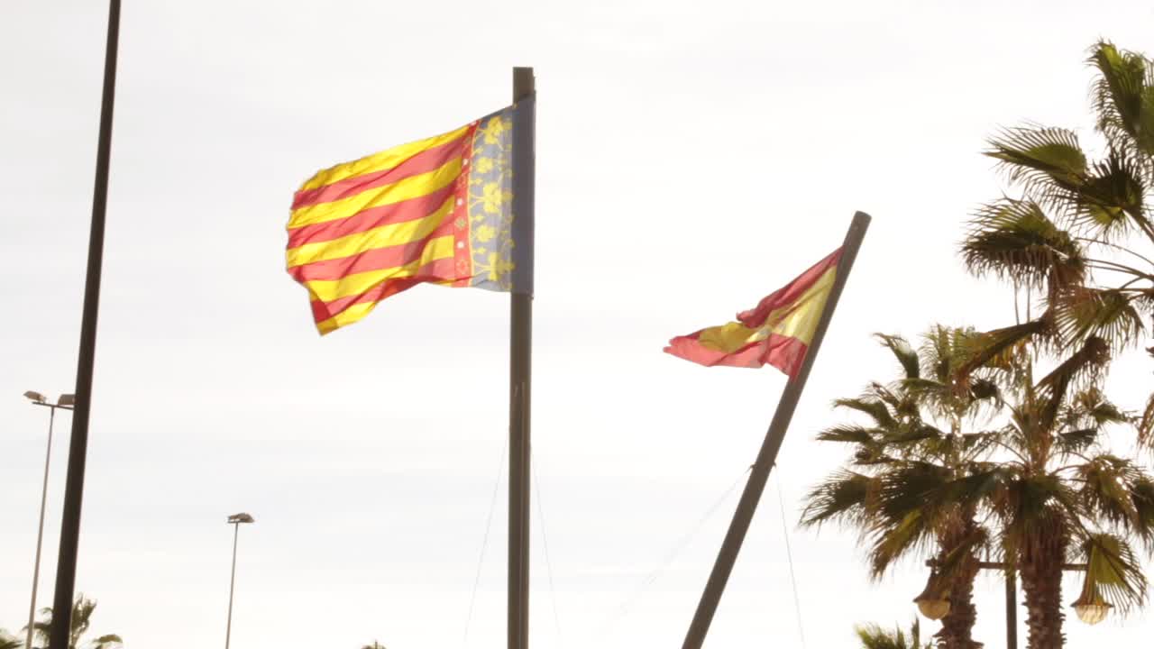 hermosa valencia españa con bandera española en cámara lenta y palmeras que fluyen en el viento