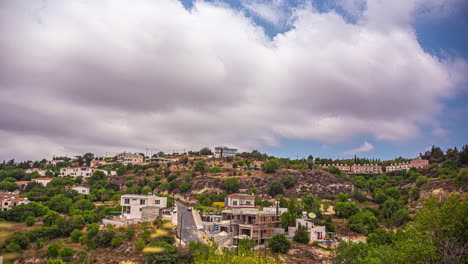 Timelapse-shot-of-town-houses-along-hilly-slope-from-Pikni-forest-viewpoint,-Cyprus-on-a-cloudy-day