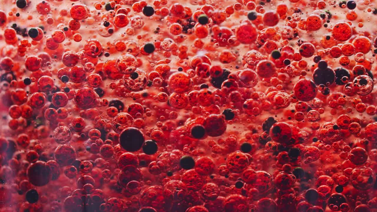 빨간색과 어두운 거품이 천천히 물속에서 땅으로 떨어지는 매크로 샷